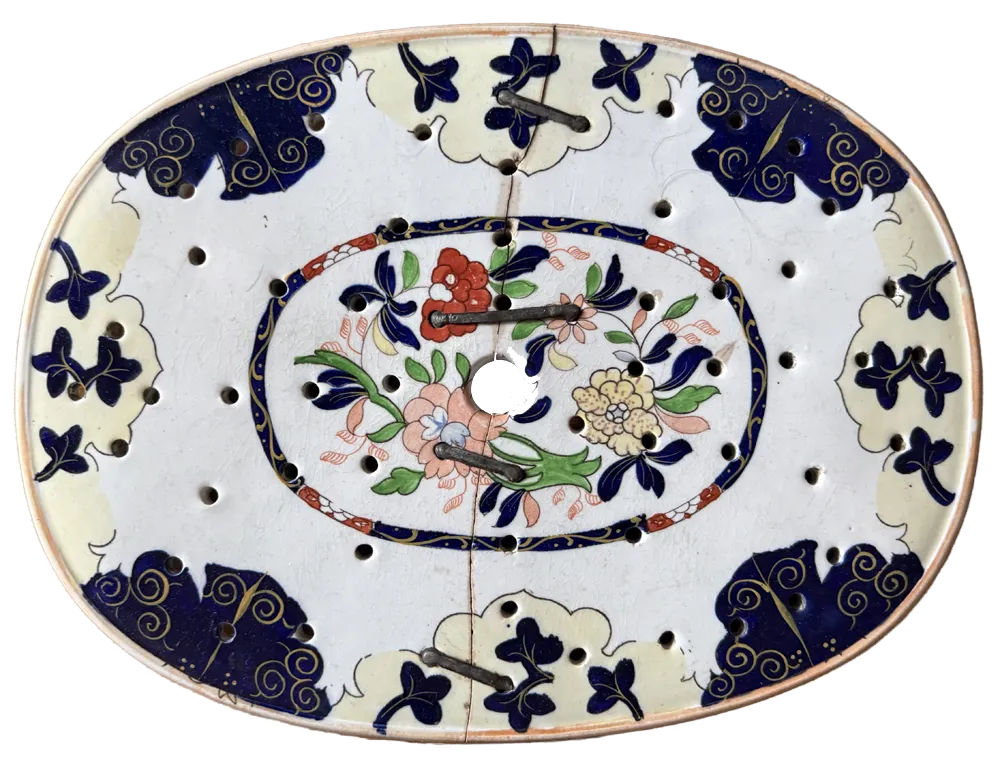 Ceramic meat strainer with rivets utilising preexisting holes, from the collection of Tomas Brown