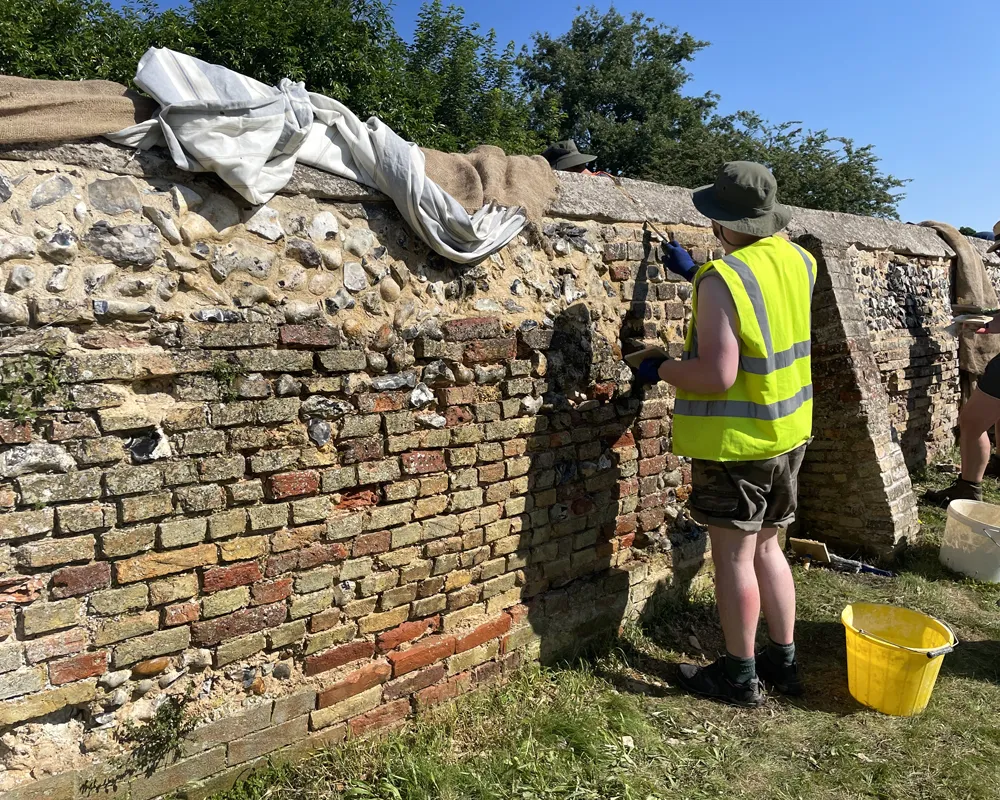 Wall section covered with sheeting to slow the drying of hot-lime mortar repointing